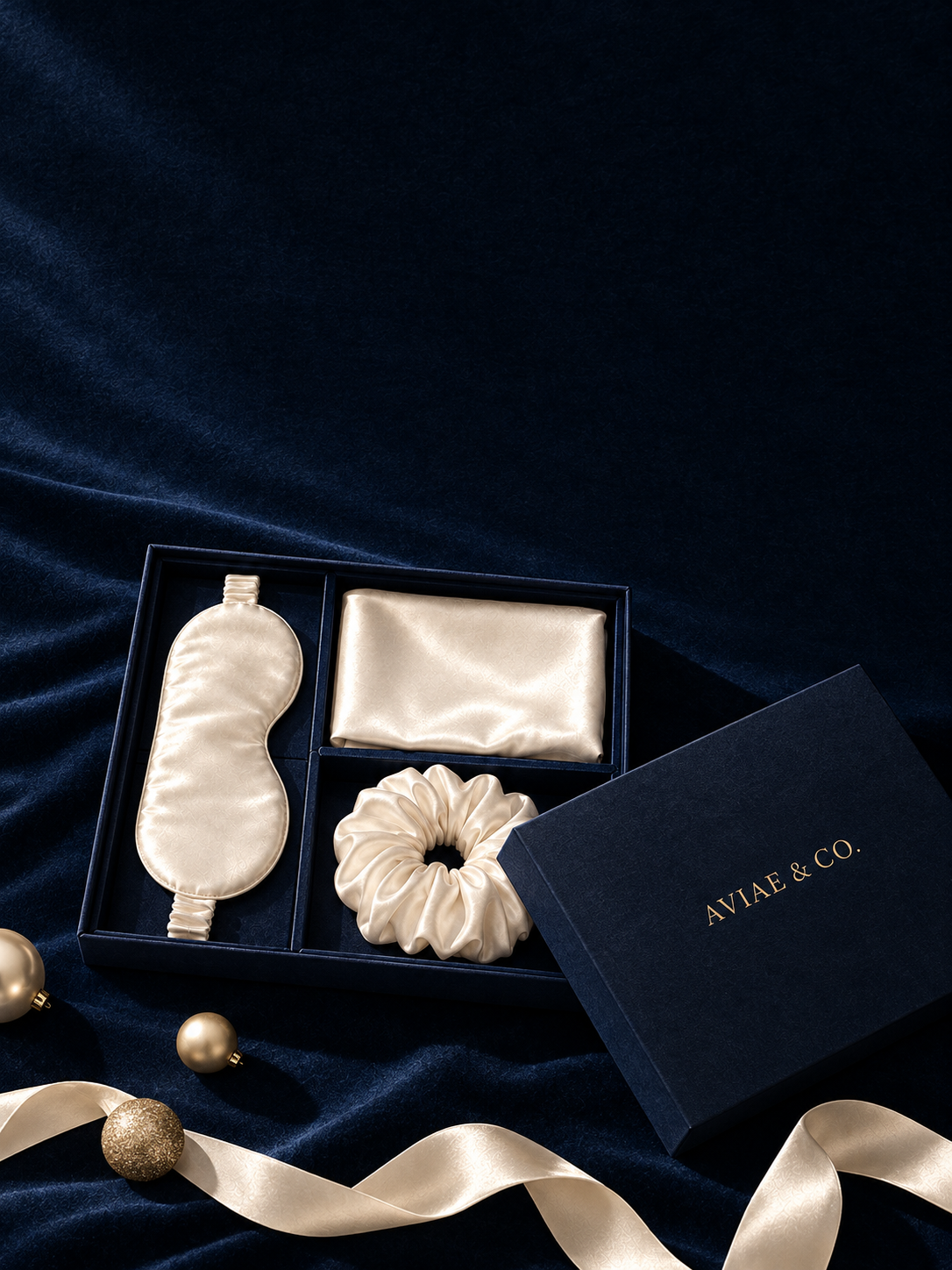 Aviae & Co. silk eye mask, pillowcase and scrunchie in the navy gift box on navy velvet with gold ornaments